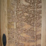 Close up of pine trees carved on Butternut door